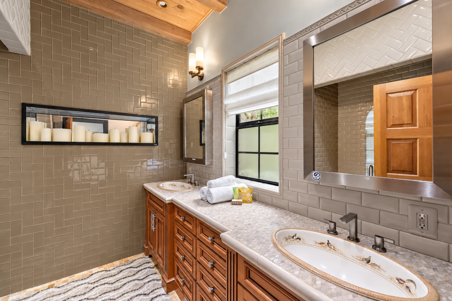 A bathroom with a long wood vanity, two basins and warm grey tile