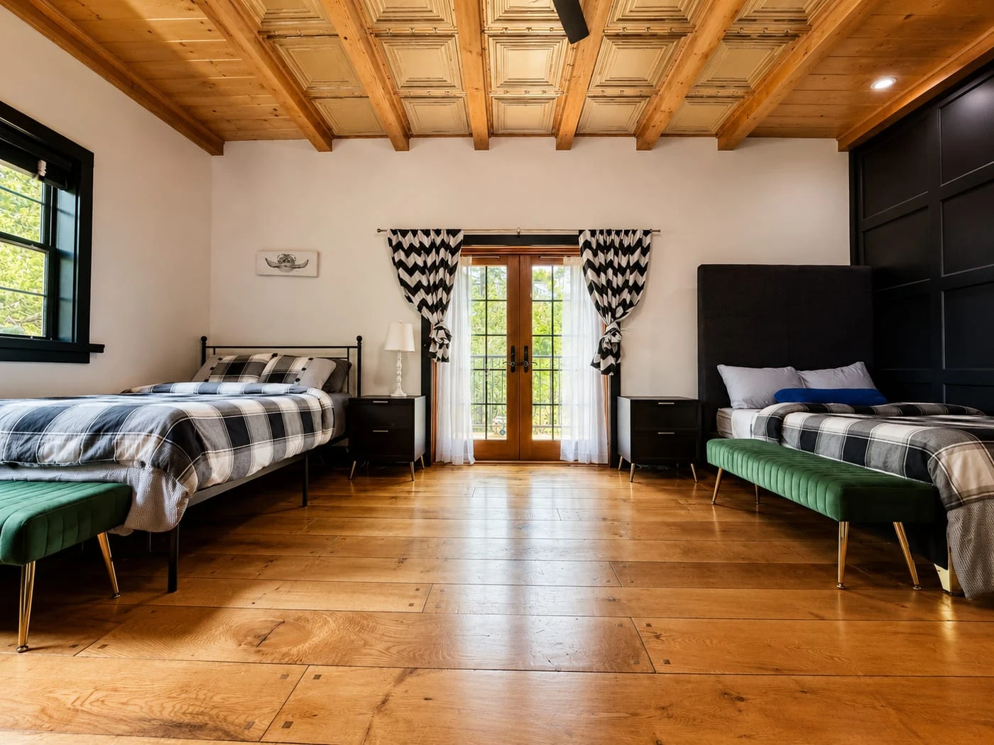 A bedroom with French doors, a coffered wood ceiling and two beds