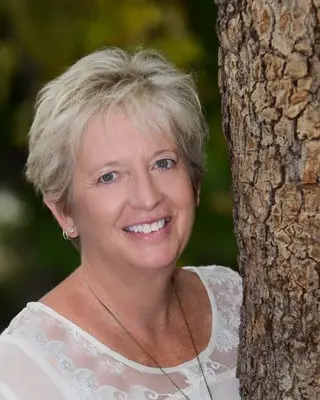 Cindy Brooks, photographed outdoors beside a pine