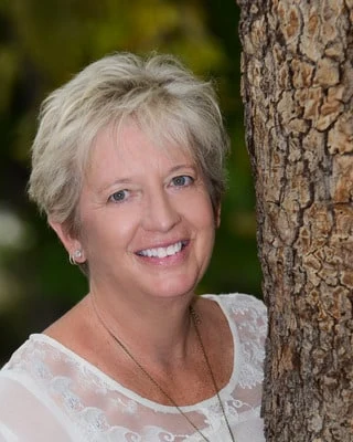 Cindy Brooks, photographed outdoors beside a pine