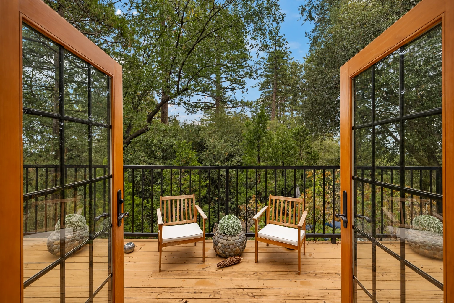 French doors standing open onto the deck and the trees beyond