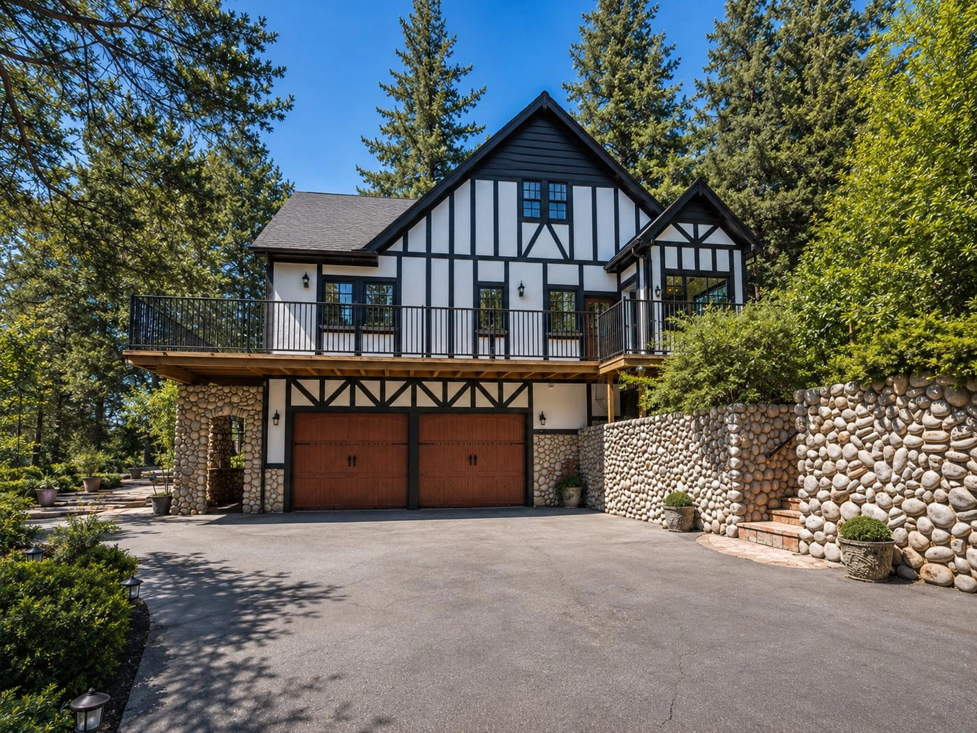 The house in daylight, its balcony and stone wall under the pines