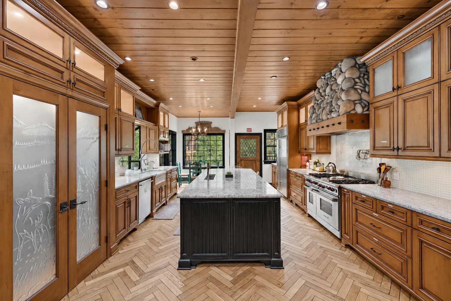 The kitchen, with a stone-topped island, a range and a herringbone floor