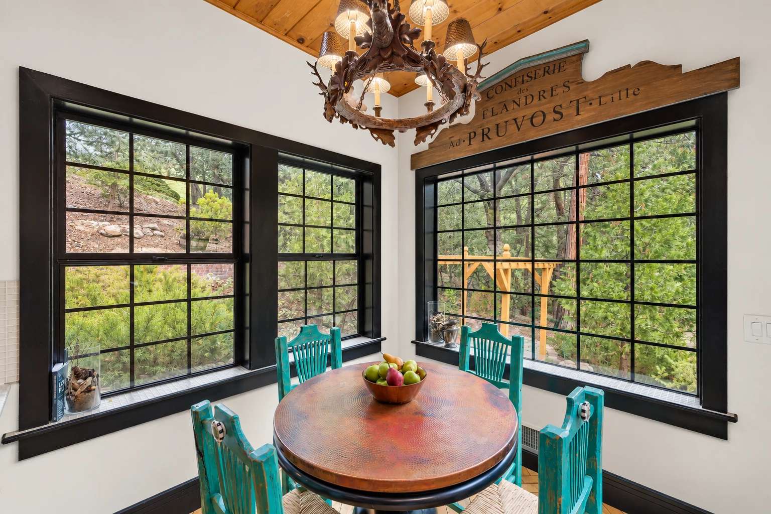A round table in a corner of tall windows, looking out into the pines