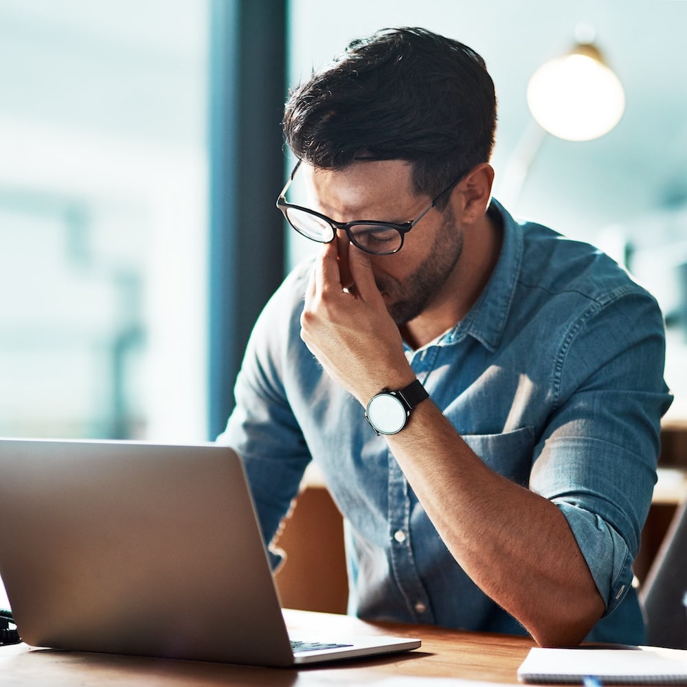 Executive professional is tired, sitting in front of laptop in California.