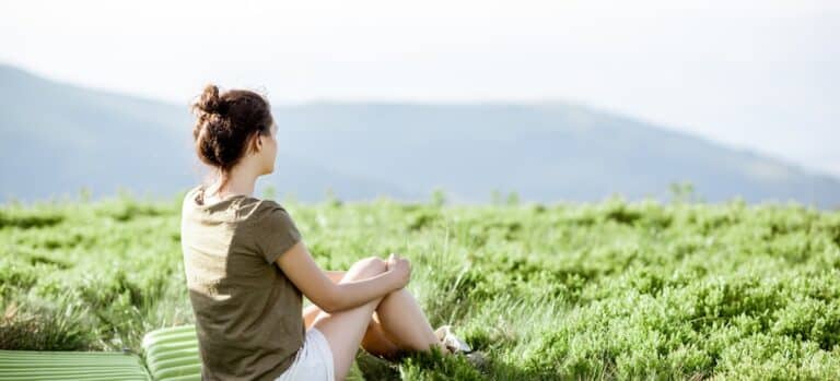 Young woman enjoying landscape view while sitting at the campsite in the mountains