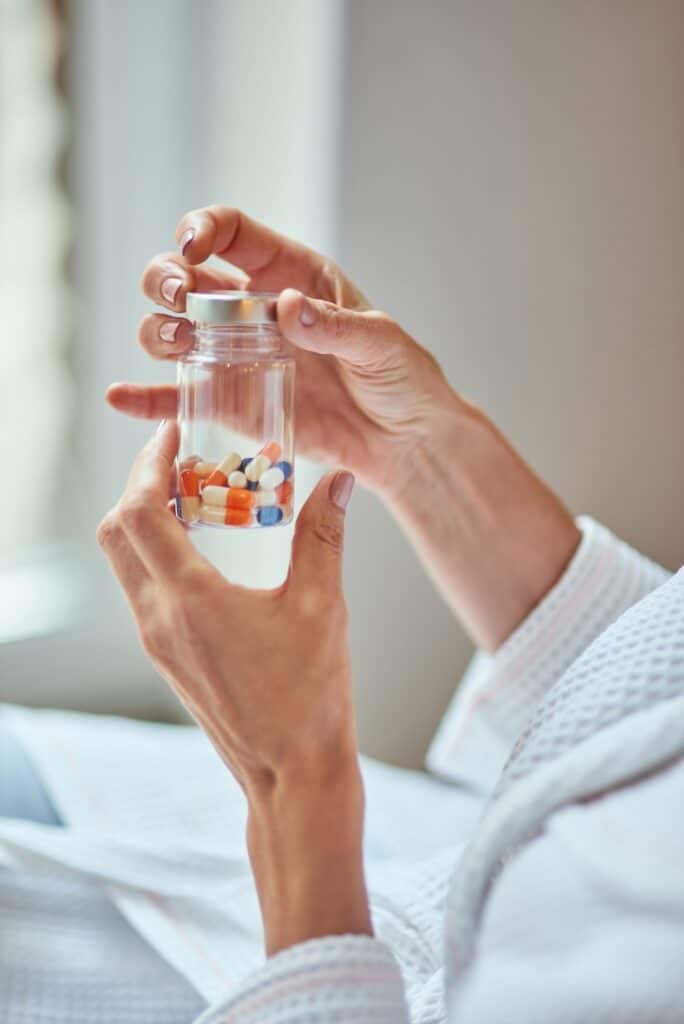 Female hands holding bottle of medications and vitamins