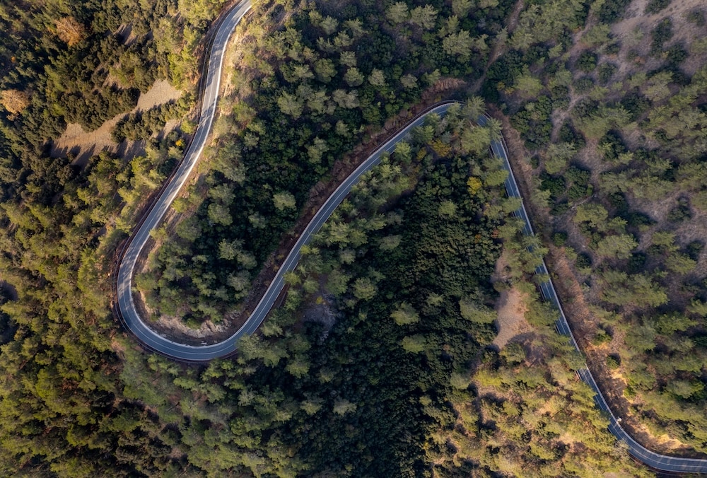 Drone aerial of mountain curved road through the forest