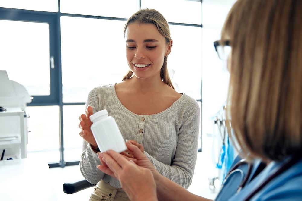 A young woman is having a detailed consultation with a healthcare professional regarding her medication options while in a modern clinic setting