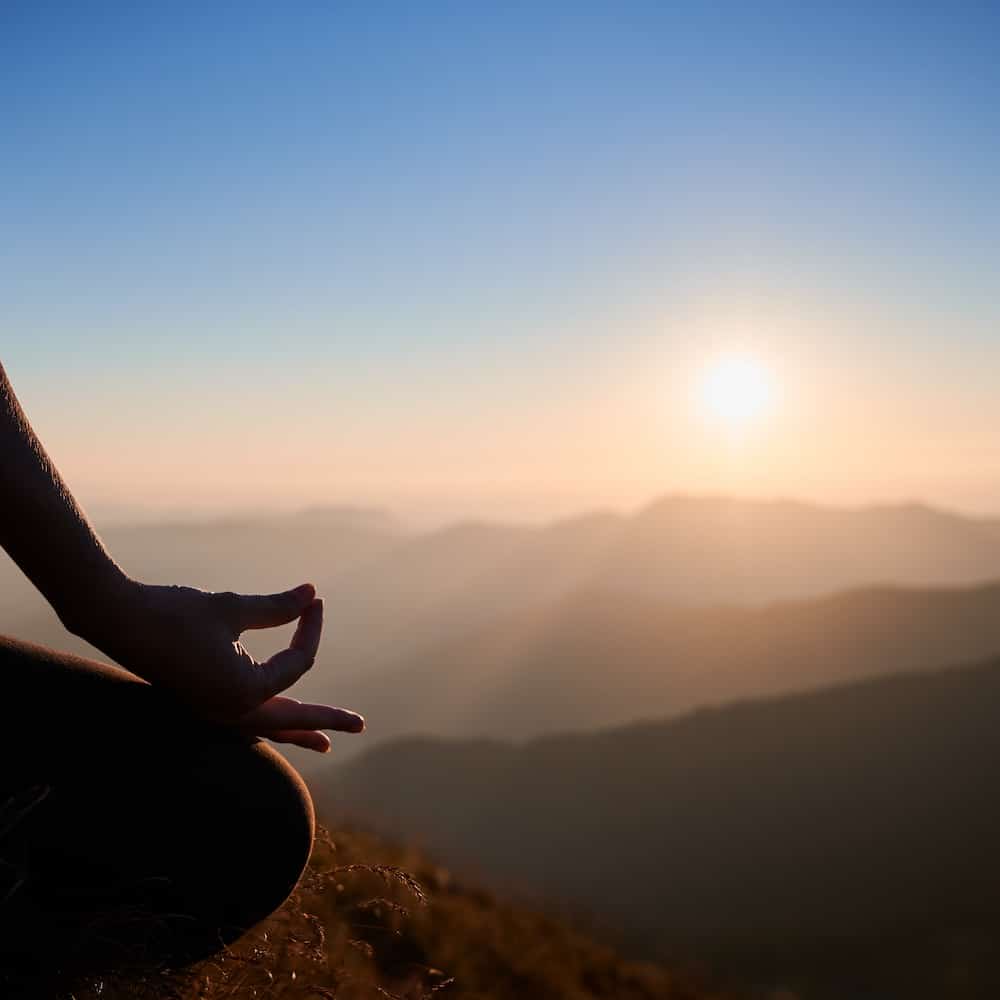 Close up view of woman's hand meditating in nature at dawn.