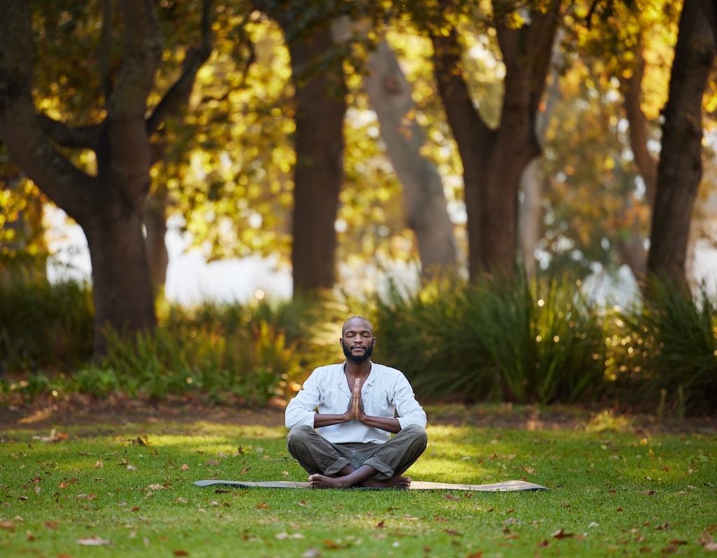 Full length shot of a handsome young man meditating while practicing yoga outside.