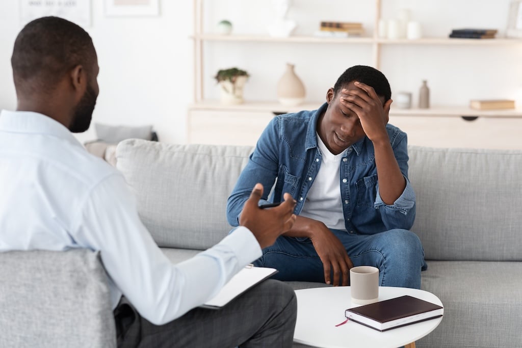 Adult man talking to psychologist during individual therapy, therapist advising coping skills for BPD.