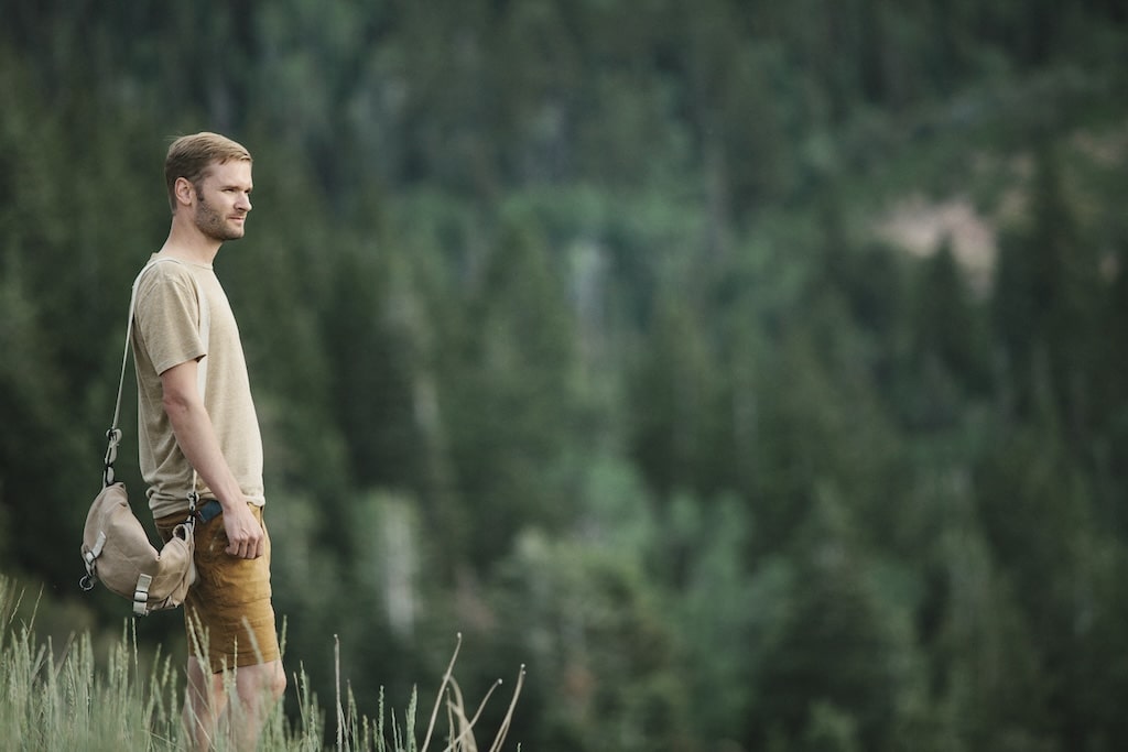 A man in the mountains standing looking around him.