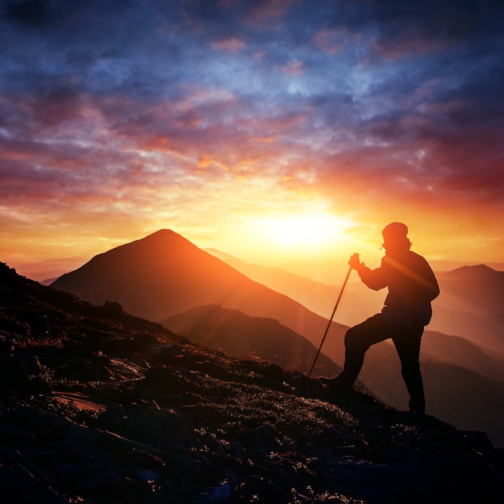 Happy man standing on a cliff at sunset.