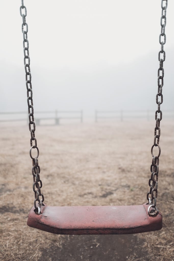 Sad empty swing at the park with fog in backgroind.