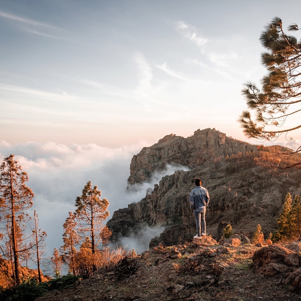 Man standing in the mountains looking out.